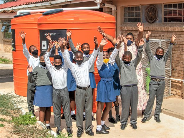 Emafini Primary School learners celebrating the receipt of a comprehensive water harvesting system from the Woolies Water Fund with educator Nomini Ncambelo.